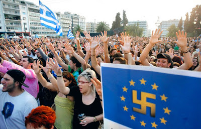 Protesters gesture as they hold a banner with an E.U. flag and swastika in the center during a peaceful rally for a sixth day, attended by thousands called through a social networking site - modeled on protests by young people in Spain, on Monday, May 30, 2011. Greece could get another euro 20 billion ($28 billion) in aid from its fellow euro countries and raise three times that through new austerity measures such as selling government property, a top European Central Bank official says. (AP Photo/Thanassis Stavrakis)